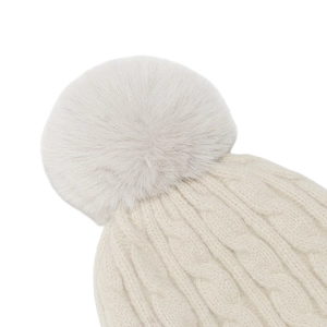 Gros plan du bonnet d'hiver crème avec maille torsadée épaisse et pompon en fausse fourrure