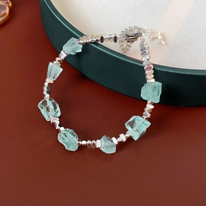 Dettaglio del bracciale con pietre blu irregolari, perline argentate e ciondolo delfino