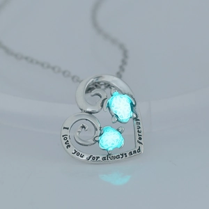 Macro shot of silver heart necklace with luminous turtles and I love you engraving