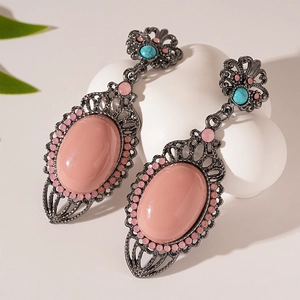 Macro detail of bohemian pink resin stone earrings with turquoise floral stud accents
