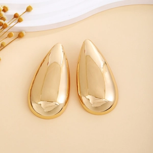 Macro detail of high-polish gold teardrop earrings with a smooth reflective mirror surface