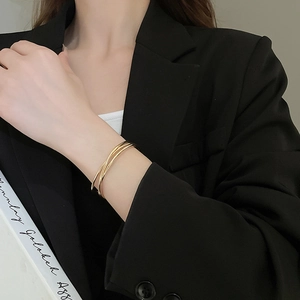 Detail of minimalist gold triple-layered intertwined bangle on a model's wrist