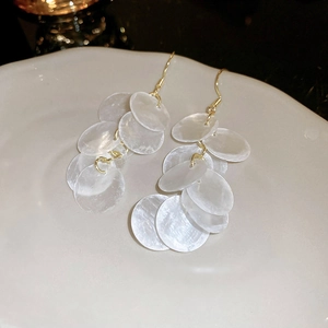 Detail of layered pearlescent shell sequins on long gold tassel drop earrings