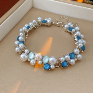 Dettaglio macro di un bracciale vintage con perle e opale blu in una scatola beige