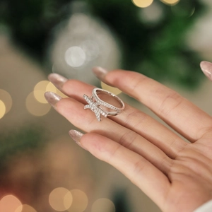 Close-up of sparkling bow-shaped silver ring with micro-pave crystals on a model hand