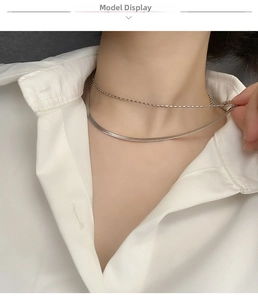 Detail of silver double-layered snake and bead chain necklace on a white shirt