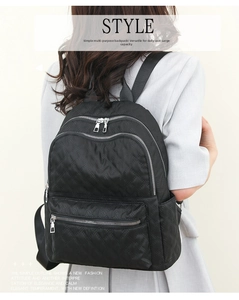 Detalle de mochila de nailon acolchado negro con compartimentos con cremallera y herrajes