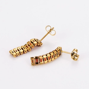 Close-up of golden bar earrings featuring rectangular red zircon stones on white background