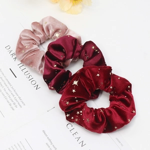 Pink and wine red velvet scrunchies with golden star pattern on minimalist white background