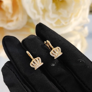 Detailed macro view of gold crown earrings set with sparkling white zircon stones