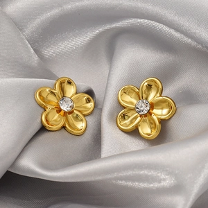 Vintage gold-plated floral stud earrings with crystal center on a luxury silk background