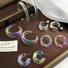 Flat lay of iridescent resin hoop earrings set with rainbow finish on silk fabric