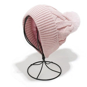 Close-up of pink knit beanie showing thick fleece lining and faux fur pompom detail