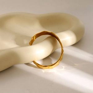 Detail of 18k gold plated stainless steel irregular open bangle on ceramic tray