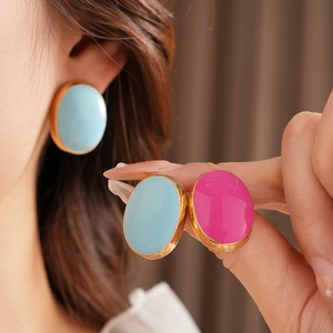 Detail view of large oval vintage earrings in blue and pink enamel with gold metal trim