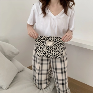 Detail shot of leopard print canvas makeup bag with a square brand label held by a model