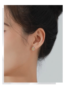 Close-up of elegant S925 silver stud earrings with pear-cut yellow gemstone and halo diamonds
