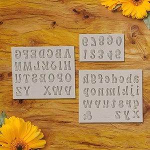 Macro shot of liquid silicone alphabet and number molds on a warm wooden background