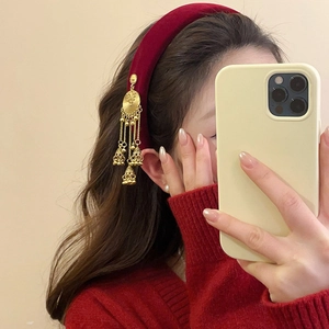 Close-up of wine red velvet headband featuring retro golden bell tassel details for women