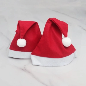 Classic red Christmas hats with white plush trim and pompom on marble background