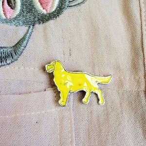 Nahaufnahme einer gelben Golden Retriever Emaille-Hundebrosche an einer rosa Tasche