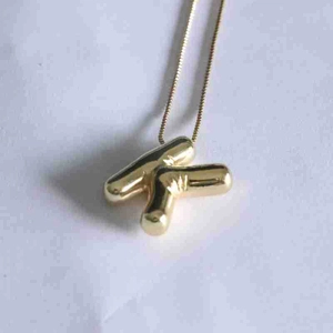 Detailed close-up of a 3D polished golden letter K pendant with a shiny bubble design
