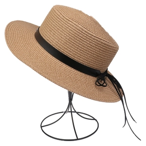 Detail view of woven straw sun hat with black faux leather band and bow on display