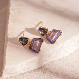 Detailed view of geometric earrings with purple trapezoid and grey triangle crystals