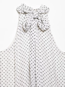 Detailed view of polka dot halter neckline with a bow tie on a white chiffon dress