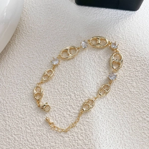 Elegante pulsera dorada con eslabones de morro de cerdo y circonitas sobre fondo beige