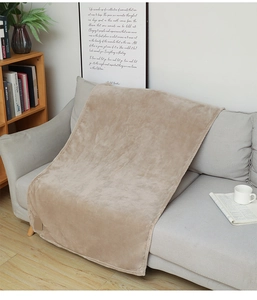Close-up of soft light brown flannel blanket textured fabric draped on a modern grey sofa