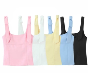 Flat lay of colorful crop tops with bow straps in pink, white, yellow, blue and black
