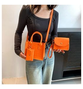 Detailed view of orange crocodile texture handbag set with shoulder strap on a model