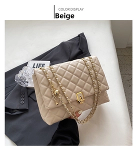 Close-up of beige quilted shoulder bag with gold chain strap and metal lock detail