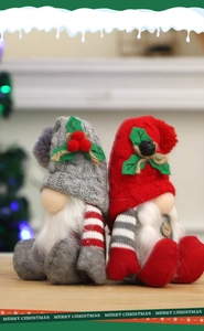Close-up of red and grey knitted Christmas gnomes with faux fur on a wooden table
