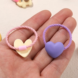 Pair of high-elastic kids heart hair ties in pink and purple resin on hand