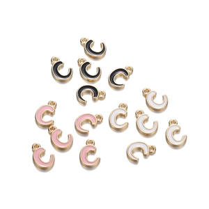 Macro detail of alloy enamel letter C pendants in black, pink, and white with gold trim