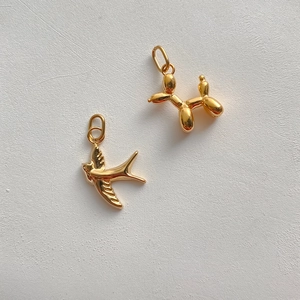 Macro shot of 14K gold-filled bird and balloon dog charms for DIY jewelry making