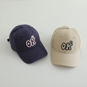 Detail of embroidered OK letters and good speech bubble on navy and beige cotton baseball caps