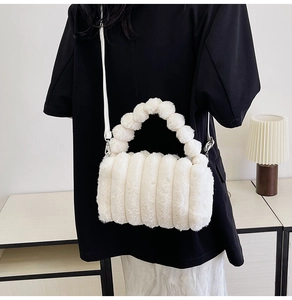 Detailed texture of white plush handbag with striped fur pattern and fuzzy ball handle
