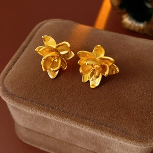 Detail van gouden lotus oorknopjes gepresenteerd op een bruine fluwelen sieradendoos