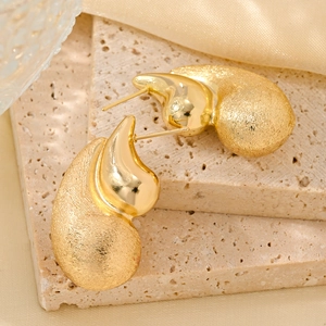 Detail of 14K gold sea snail earrings featuring mixed polished and brushed metal textures