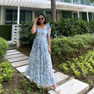 Detail of blue floral maxi dress featuring bow shoulder straps and tiered skirt layers