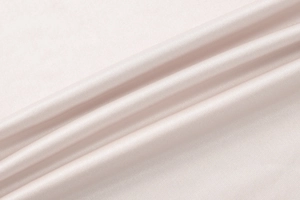 Macro detail of glossy beige silk fabric texture with soft drapes and elegant sheen