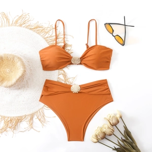 Detail of rust orange bikini featuring golden shell buckles with stylish beach accessories