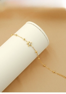 Detailed shot of a gold titanium steel necklace with a delicate five-petal flower pendant
