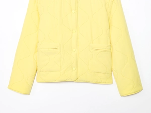Detailed close-up of yellow wave-quilted jacket with buttons and a small stand collar