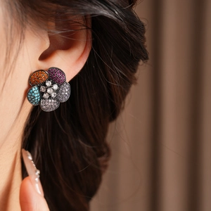 Close-up of vintage floral earrings with colorful zircons worn by a female model