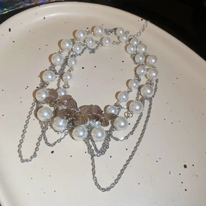 Detailed macro view of double-layered pearl necklace with silver butterfly pendants