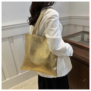 Detailed view of gold crocodile embossed tote bag with elegant metallic finish on shoulder
